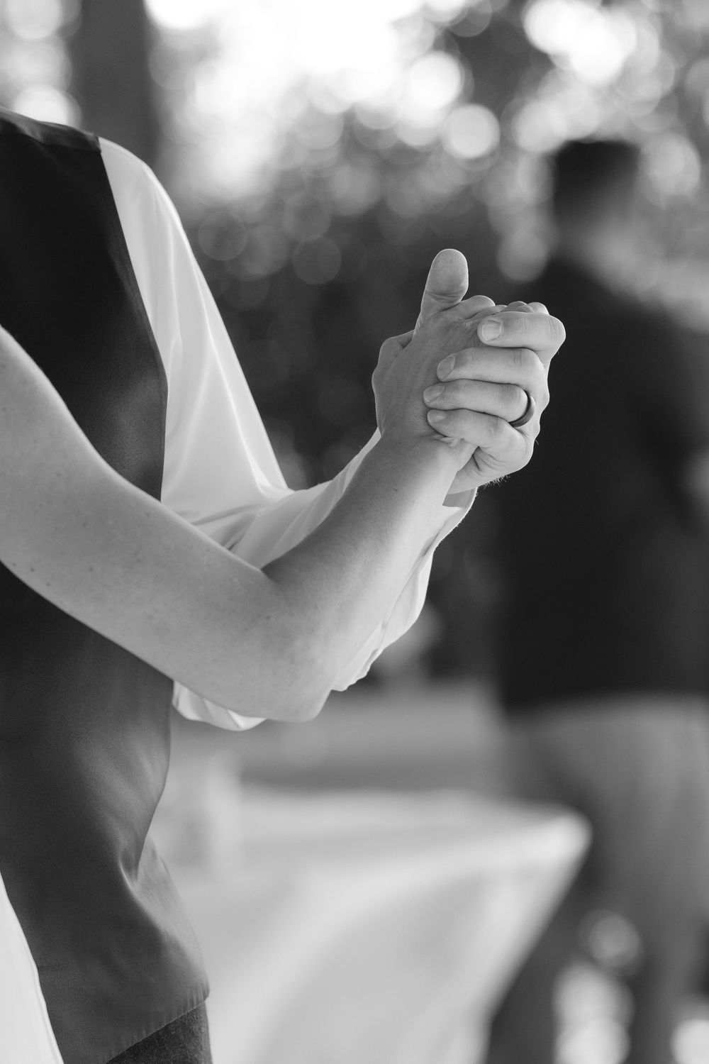 Black and white close-up of joined hands during a romantic wedding dance moment.