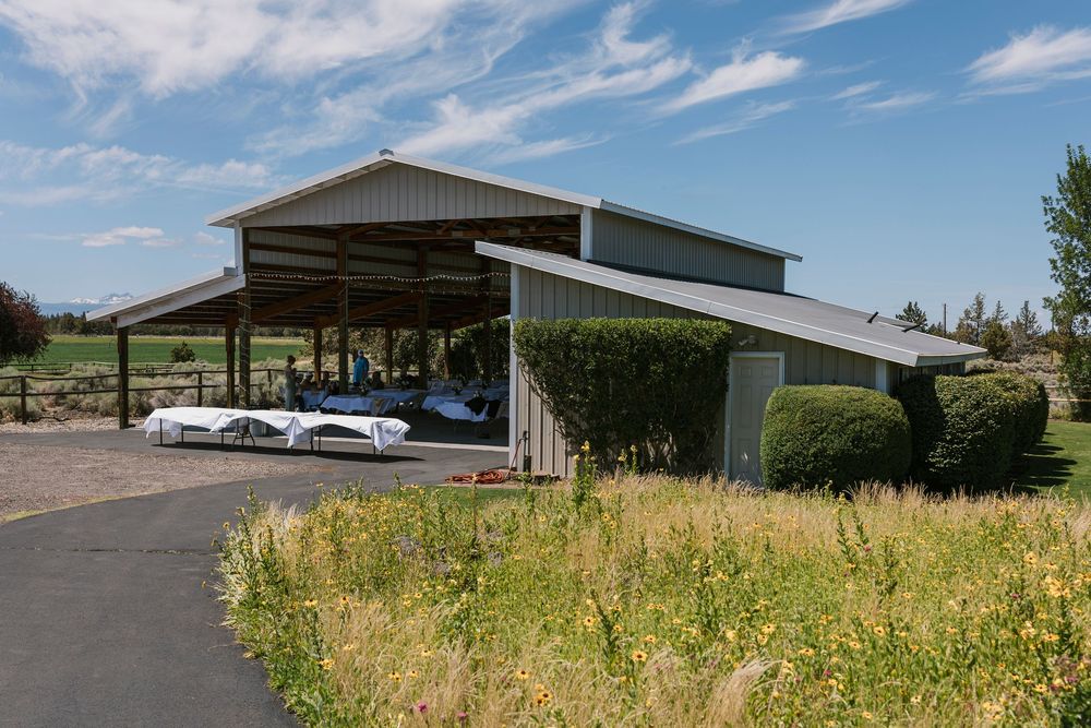 Rural venue exterior buildings and parking area under blue skies with scattered clouds.