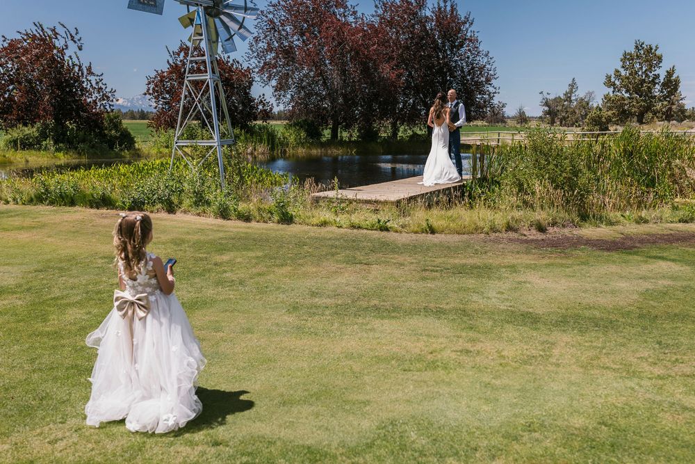 Bride walking across a green lawn with wedding dress train flowing behind her.