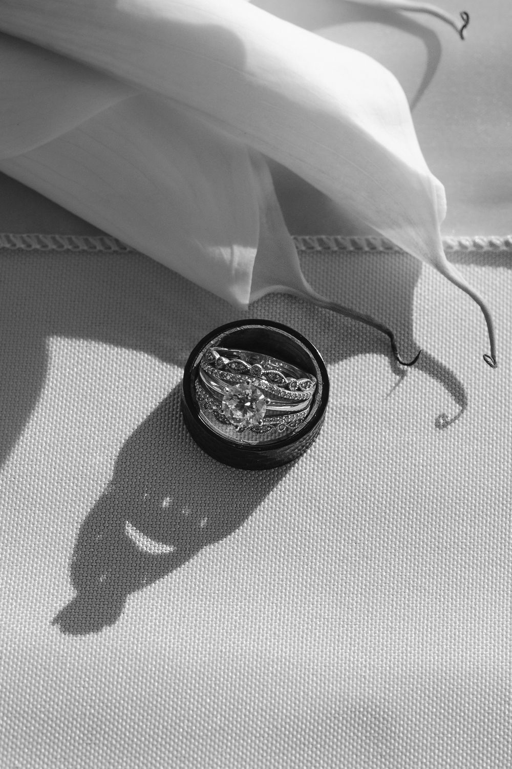 Black and white detail shot showing jewelry pieces on a textured surface with dramatic shadows.