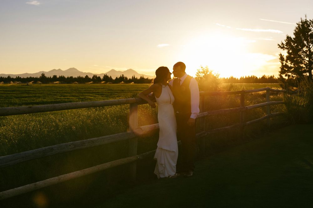Silhouettes stand against a dramatic sunset sky over rural farmland.