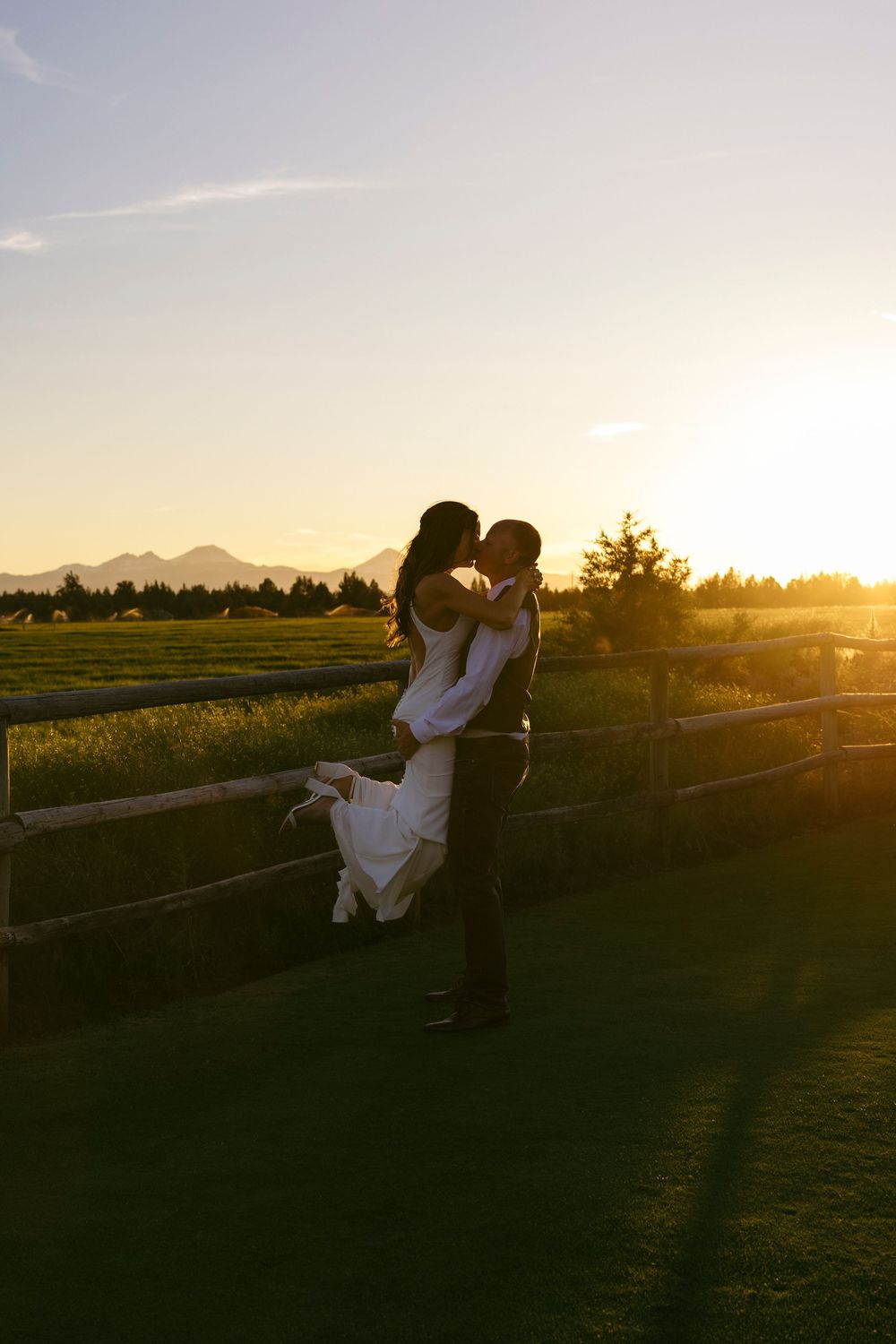 Silhouettes of a couple against a stunning mountain sunset during their wedding celebration.
