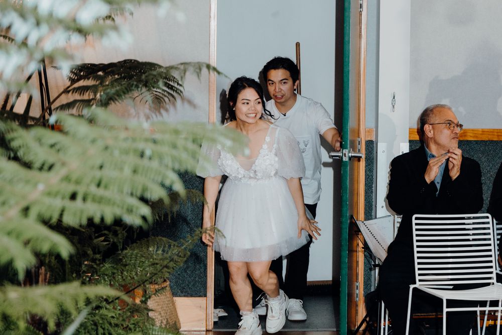 Wedding reception candid moment in a venue decorated with tropical ferns.