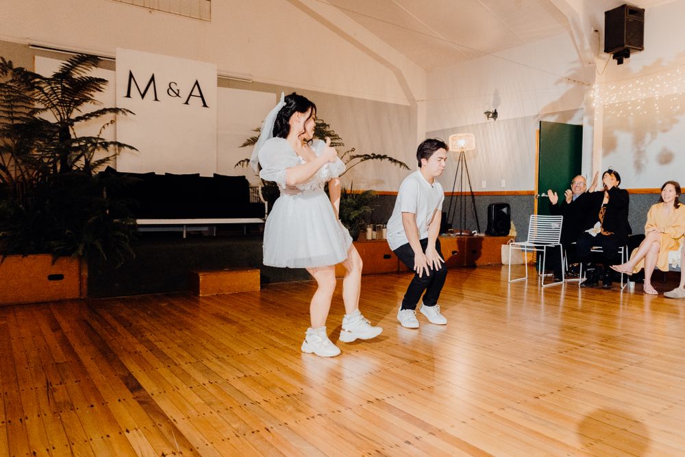 A choreographed dance performance on a wooden floor with M&A signage and potted plants in the background.
