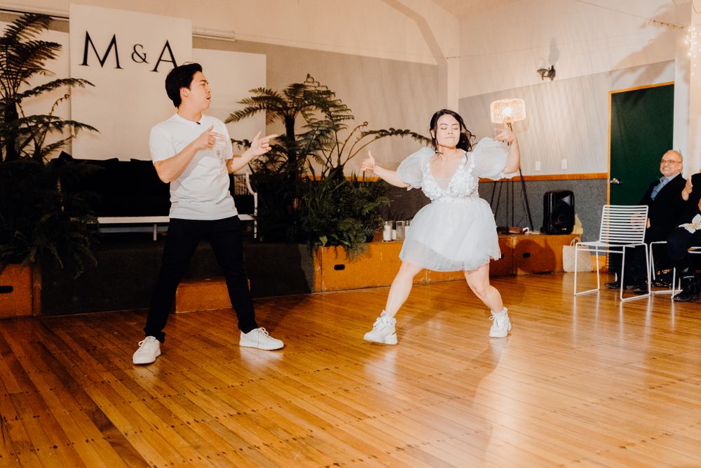Dynamic dance routine being performed in a bright indoor space with hardwood floors and decorative plants.