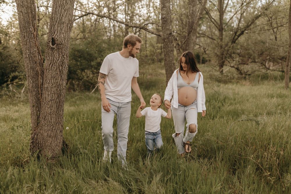 Family walking together holding hands in a natural wooded setting.