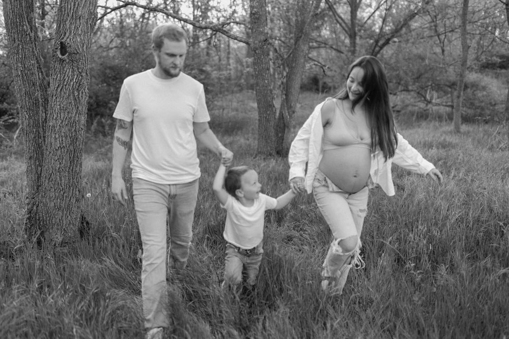 Black and white photo of a family walking hand in hand through tall grass.