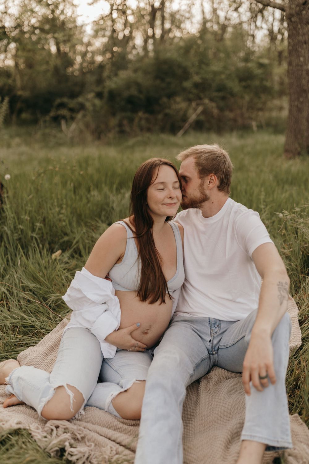 An intimate maternity photoshoot in a natural outdoor setting during golden hour.