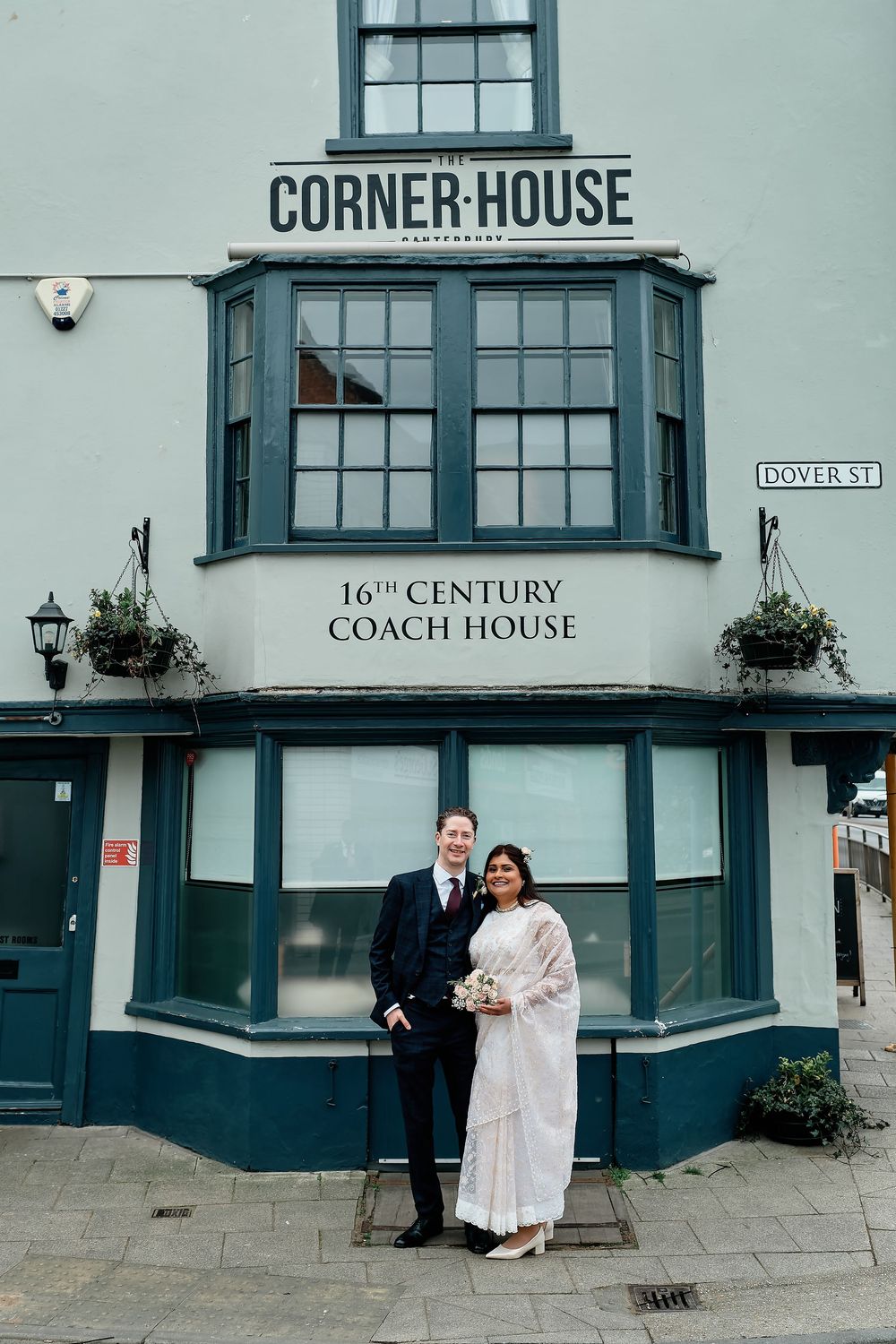 A vintage style coach house pub with teal-colored trim and bay windows stands on a corner with 'Corner House' signage above.