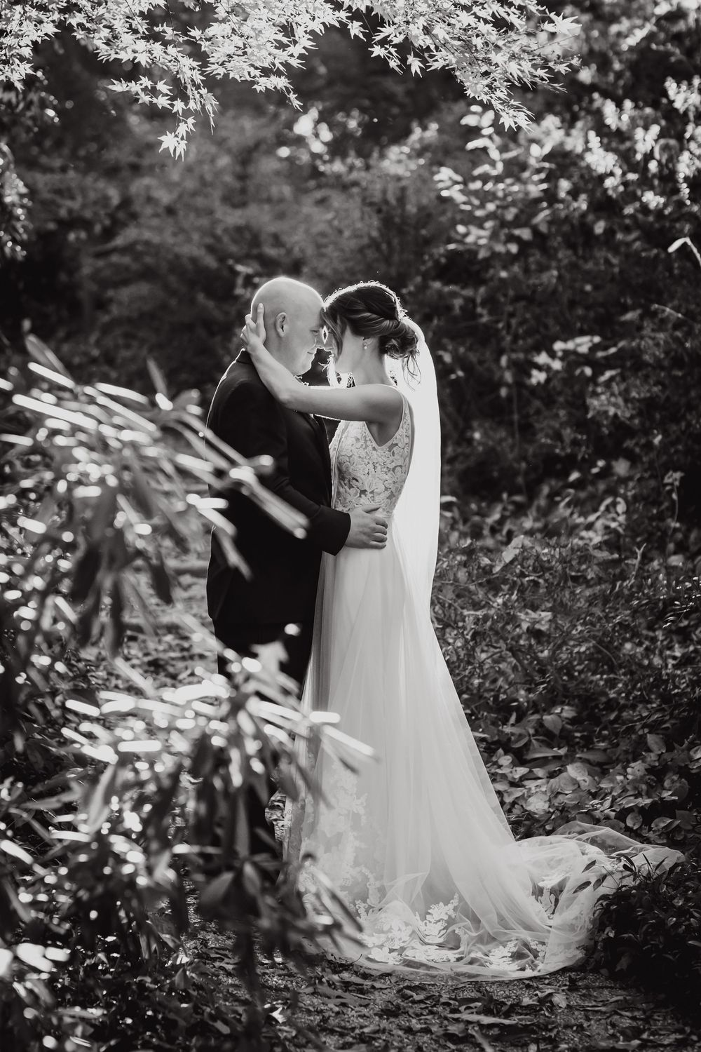 A romantic black and white wedding photoshoot sequence showing a couple embracing in a lush garden setting.