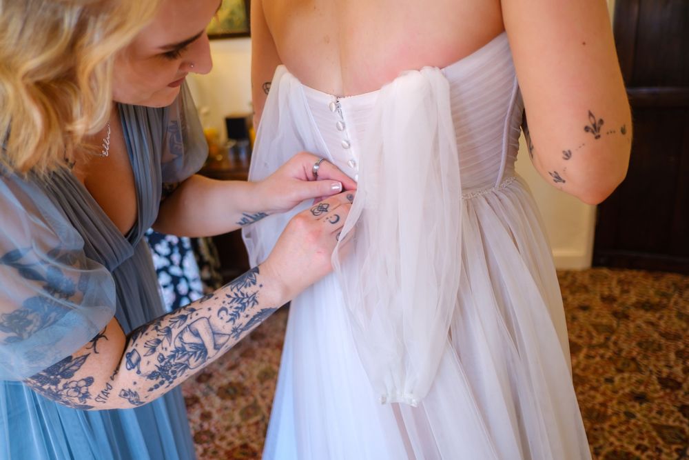 Brides sister helping her with her dress before the ceremony.