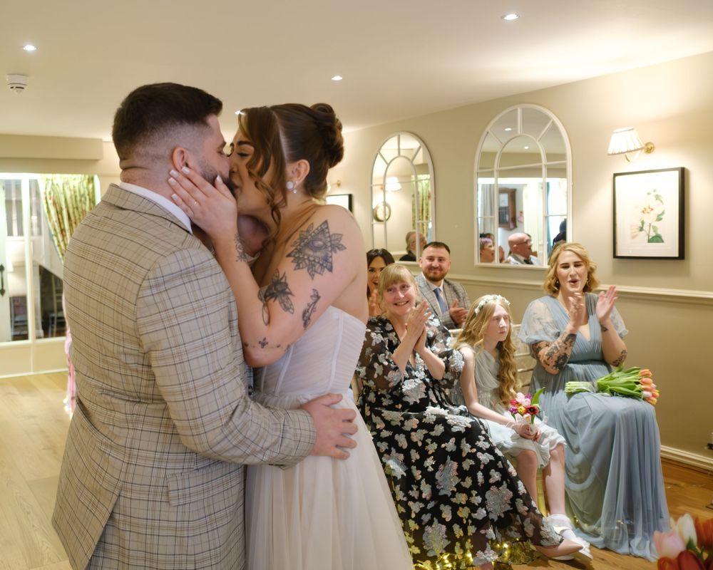 Bride and groom kissing at the front of the aisle at Holdsworth House.