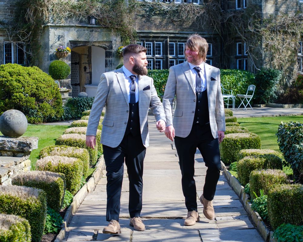 Groom and best man walking down the path in front of Holdsworth House, informal photograph