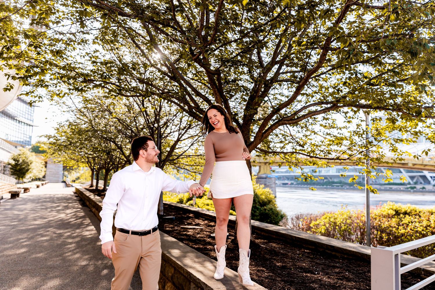 A couple celebrates joyfully with raised arms while descending a floral-decorated staircase.
