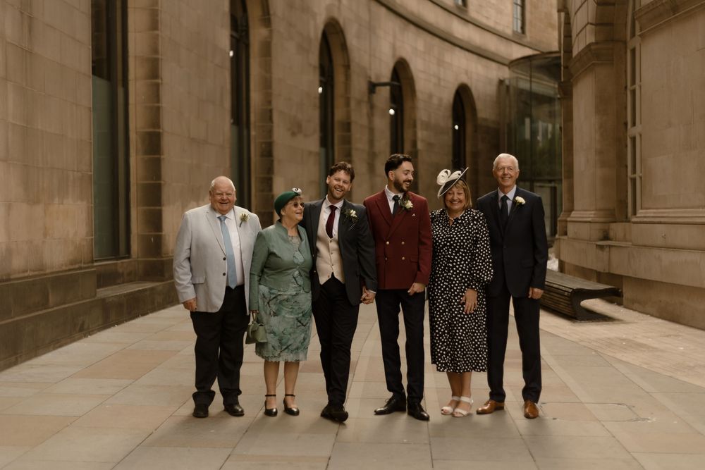 A group of formally dressed individuals walking together through an elegant stone archway corridor.