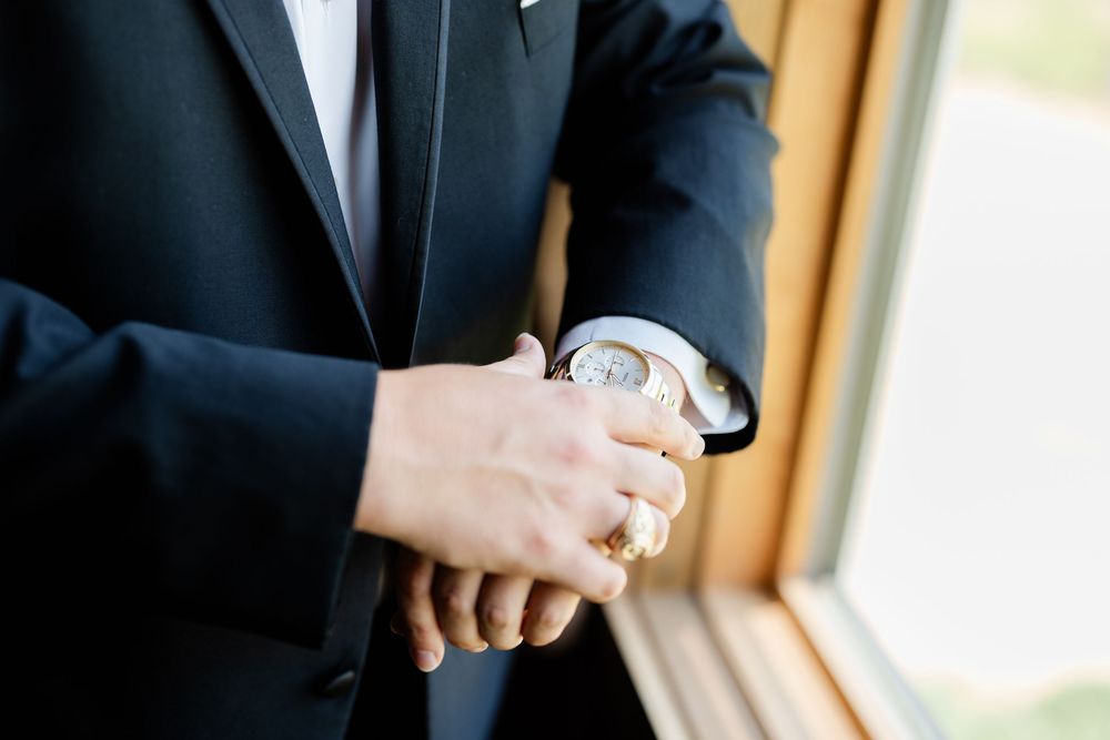 A close-up shot of a formal watch being worn with a black suit jacket.