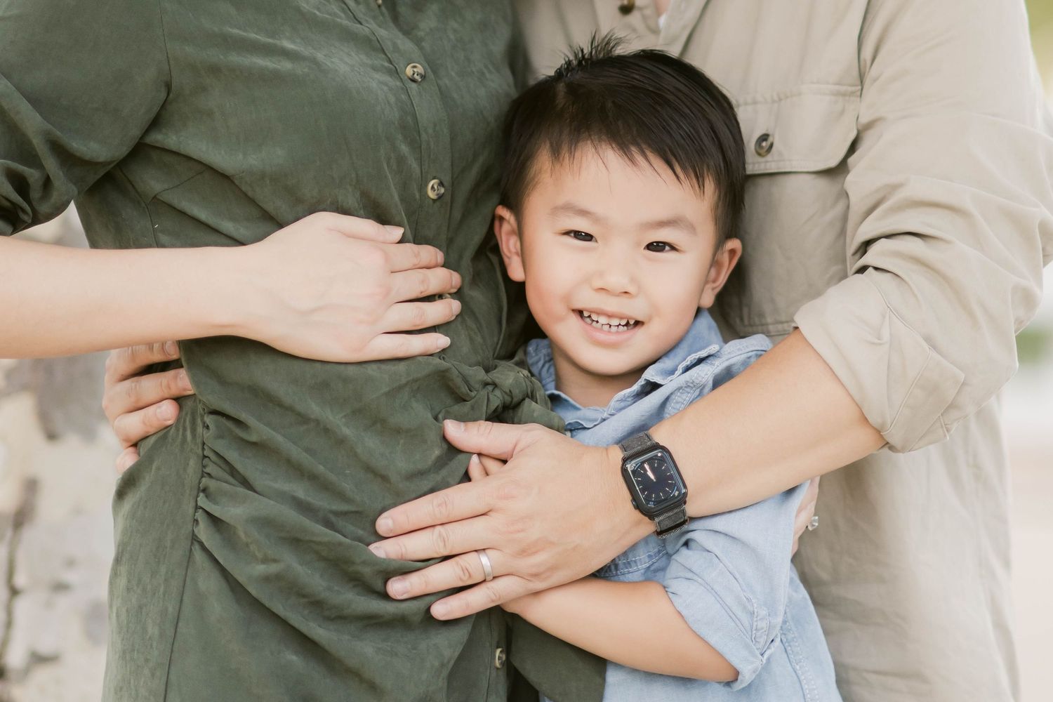 A family walks together on a sandy path holding hands while wearing casual fall clothing.
