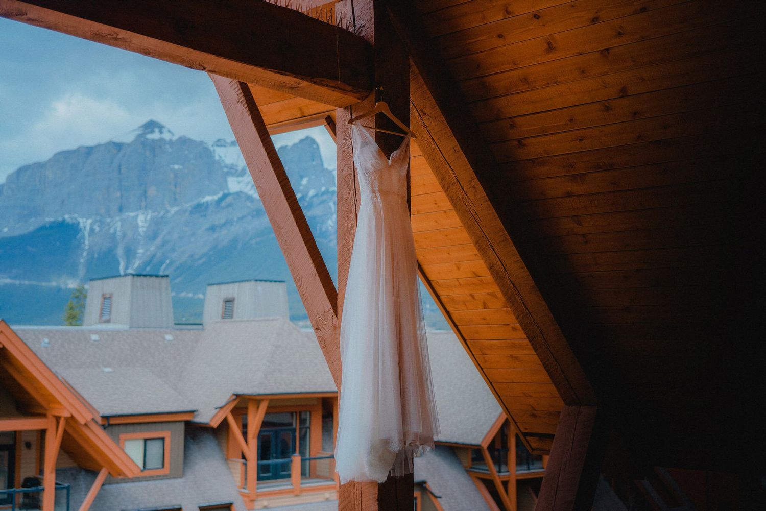 Rustic wooden beams frame a mountain view through large windows.
