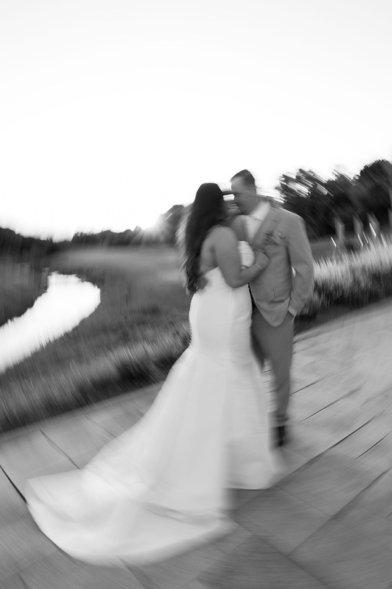 Artistic black and white motion blur of newlyweds walking along a path.