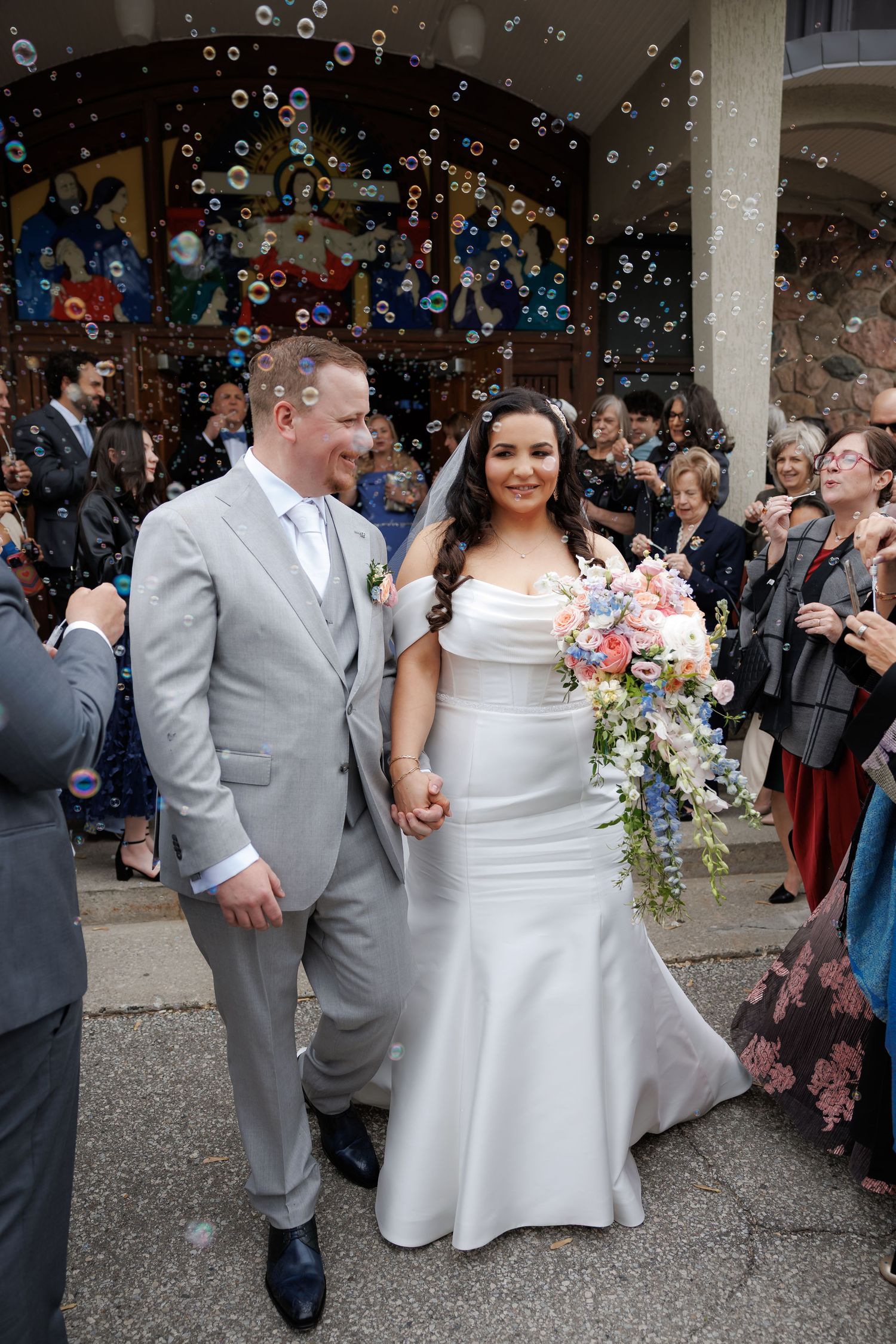Joyful wedding exit with guests blowing bubbles outside a building entrance.