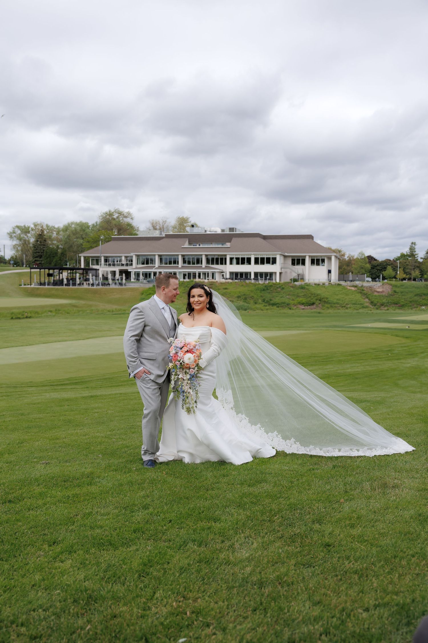 Wedding portrait on a golf course with clubhouse in background.