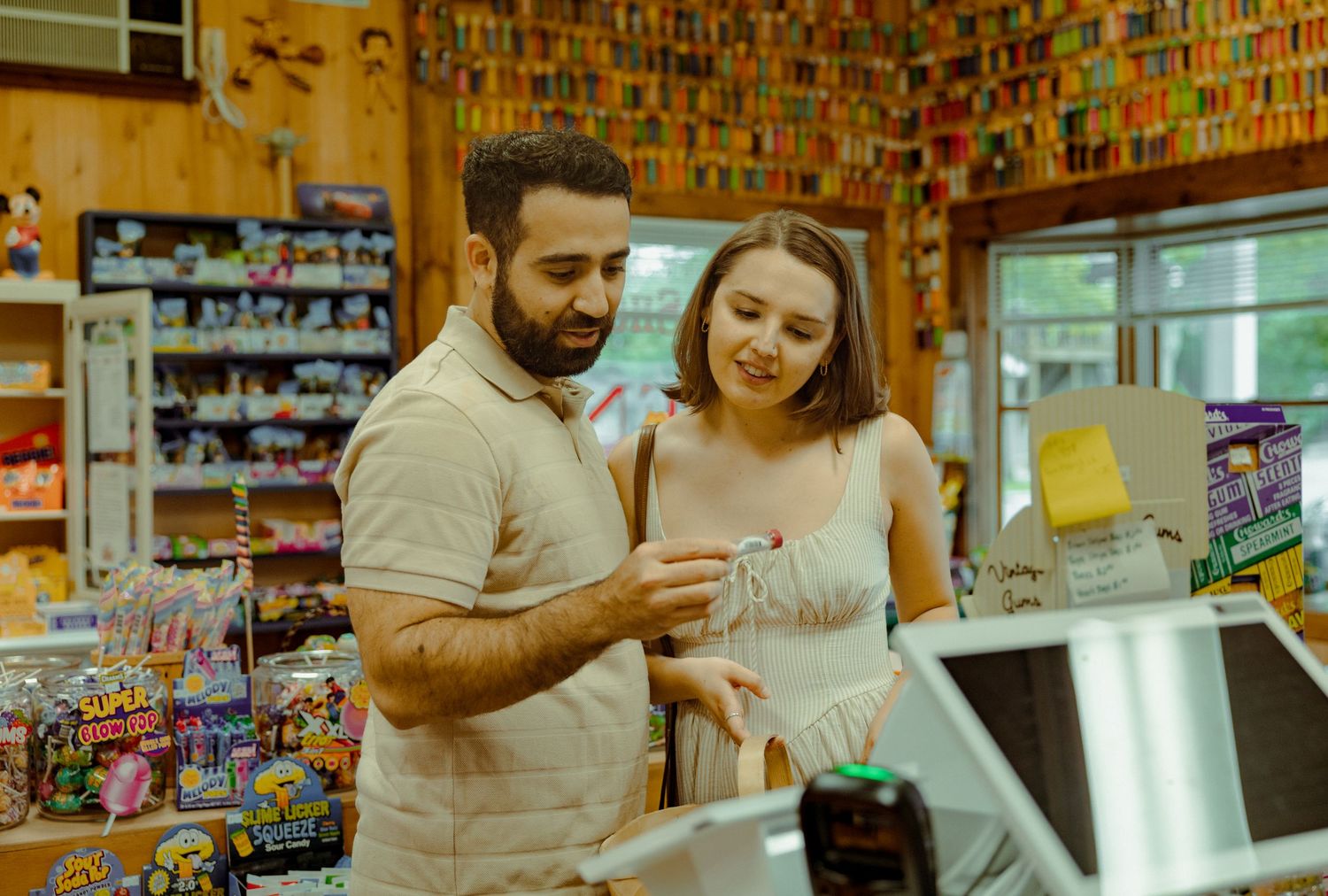 Two people shop together while looking at items inside a small convenience store with colorful shelves.