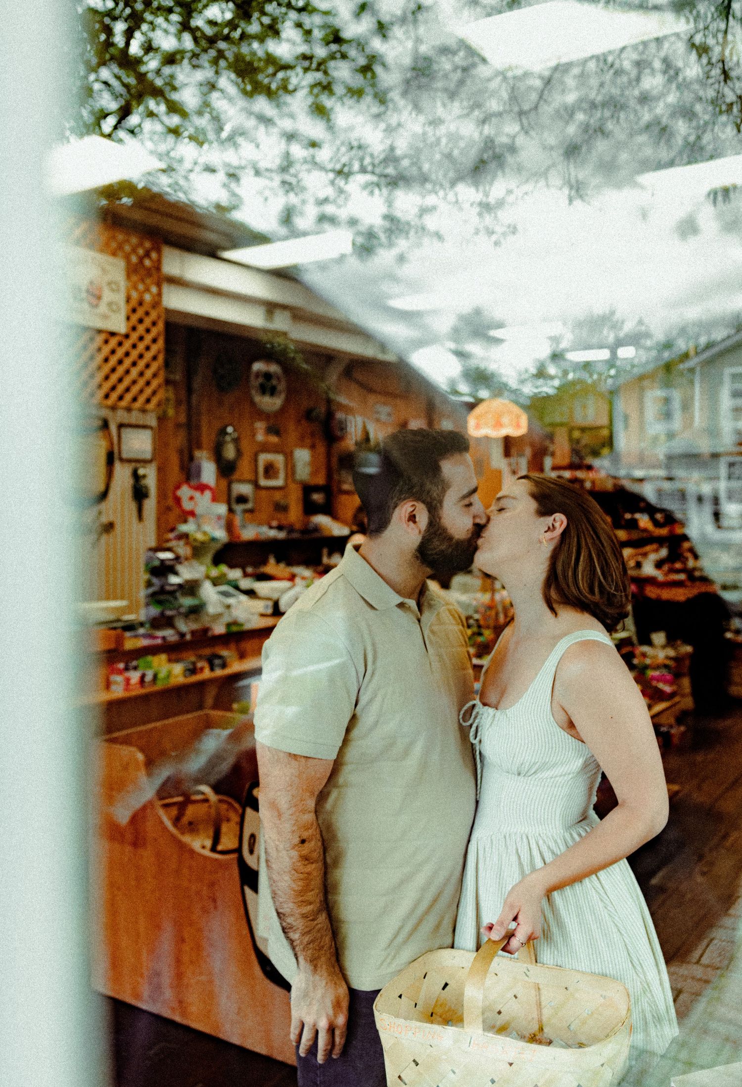 A couple shares an intimate moment while shopping at a rustic market with wooden displays and produce stands.
