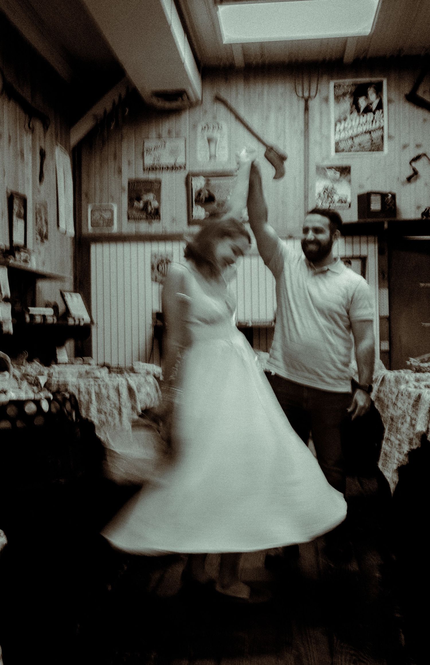 A couple dancing together in a rustic room decorated with vintage items and wooden paneled walls.