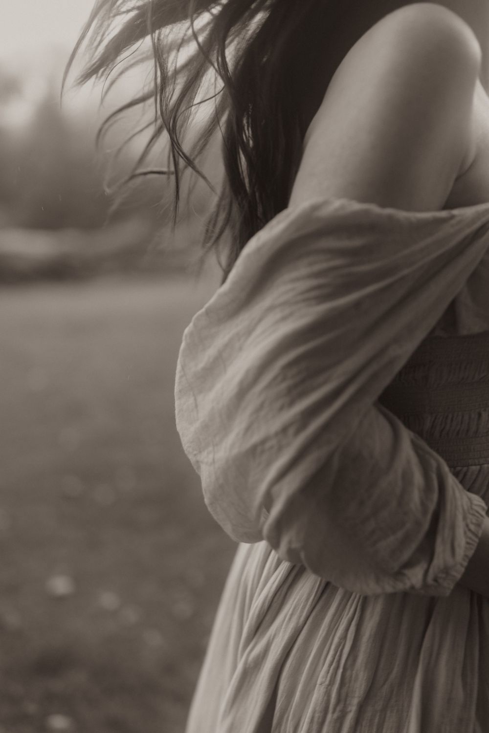 Side profile of a flowing dress and windswept hair captured in artistic black and white photography.