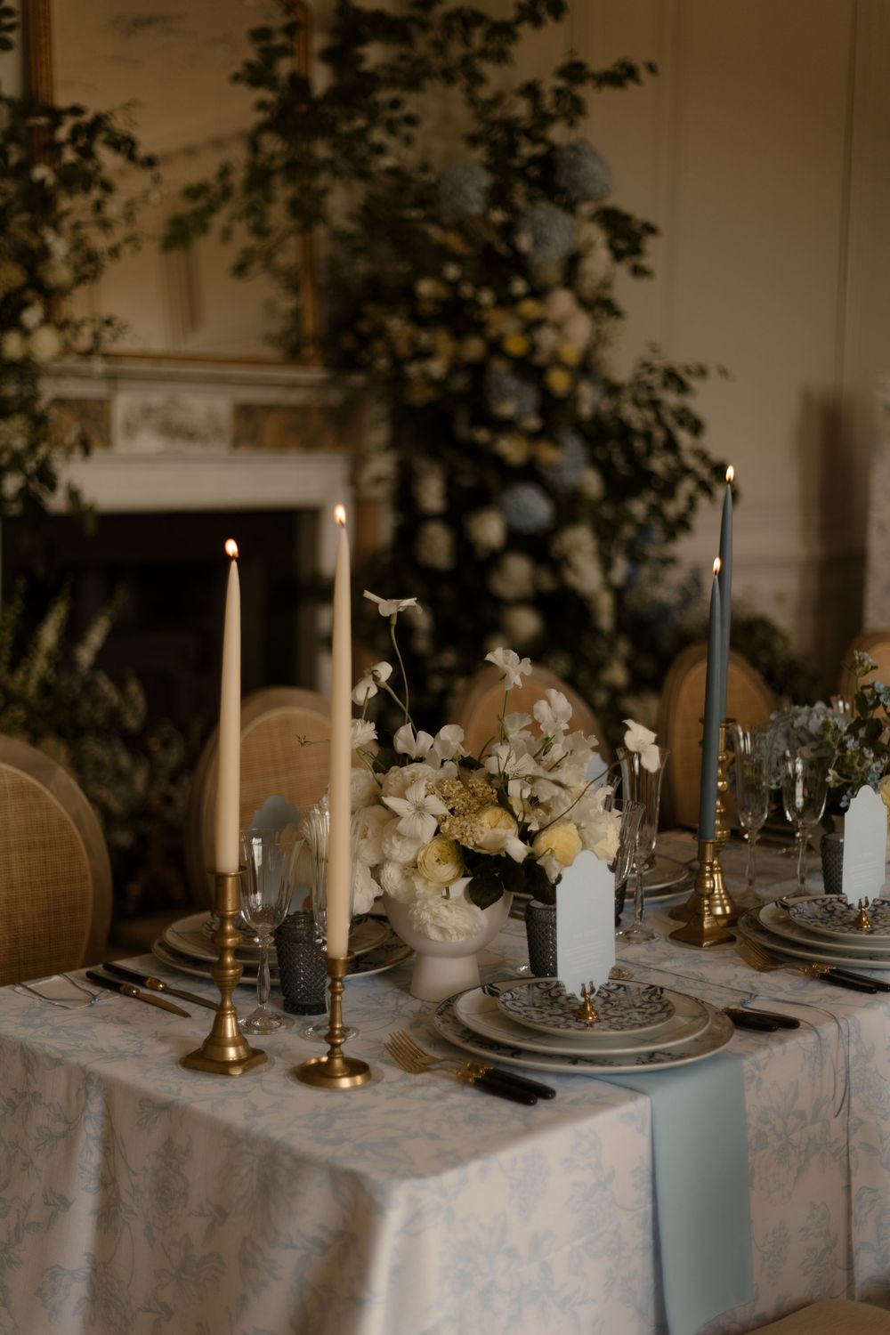 Elegant wedding table setting with gold candles, white flowers and lace tablecloth in a romantic indoor setting.