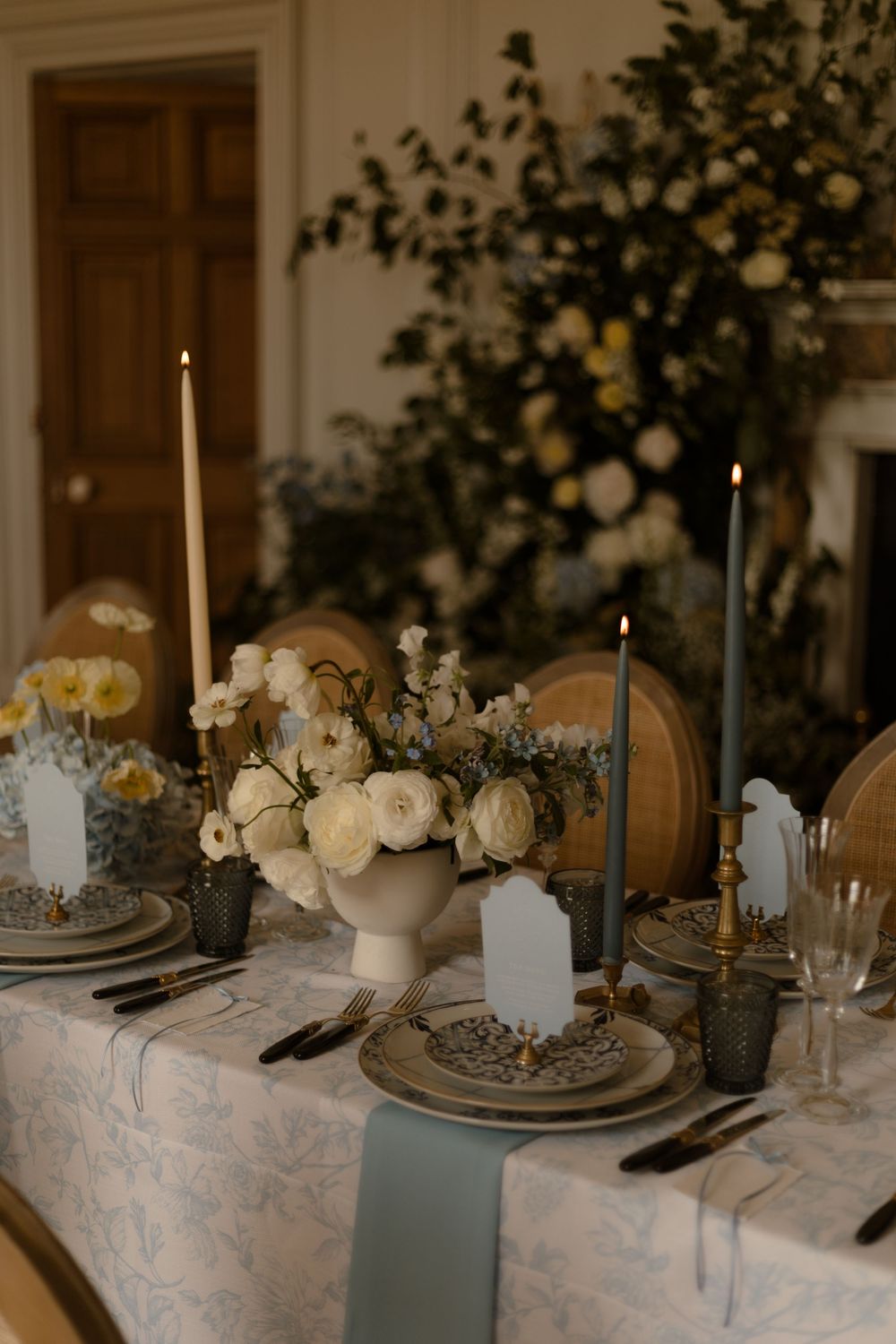 Intimate table setting with white roses, taper candles and vintage plates on a delicate lace tablecloth.