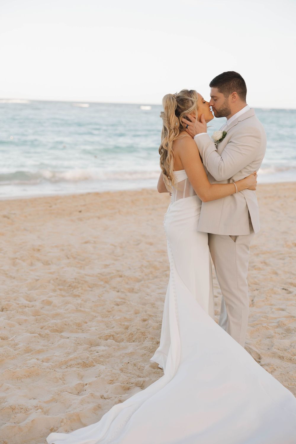 A romantic moment on a sandy beach with a long white wedding dress flowing in the breeze.