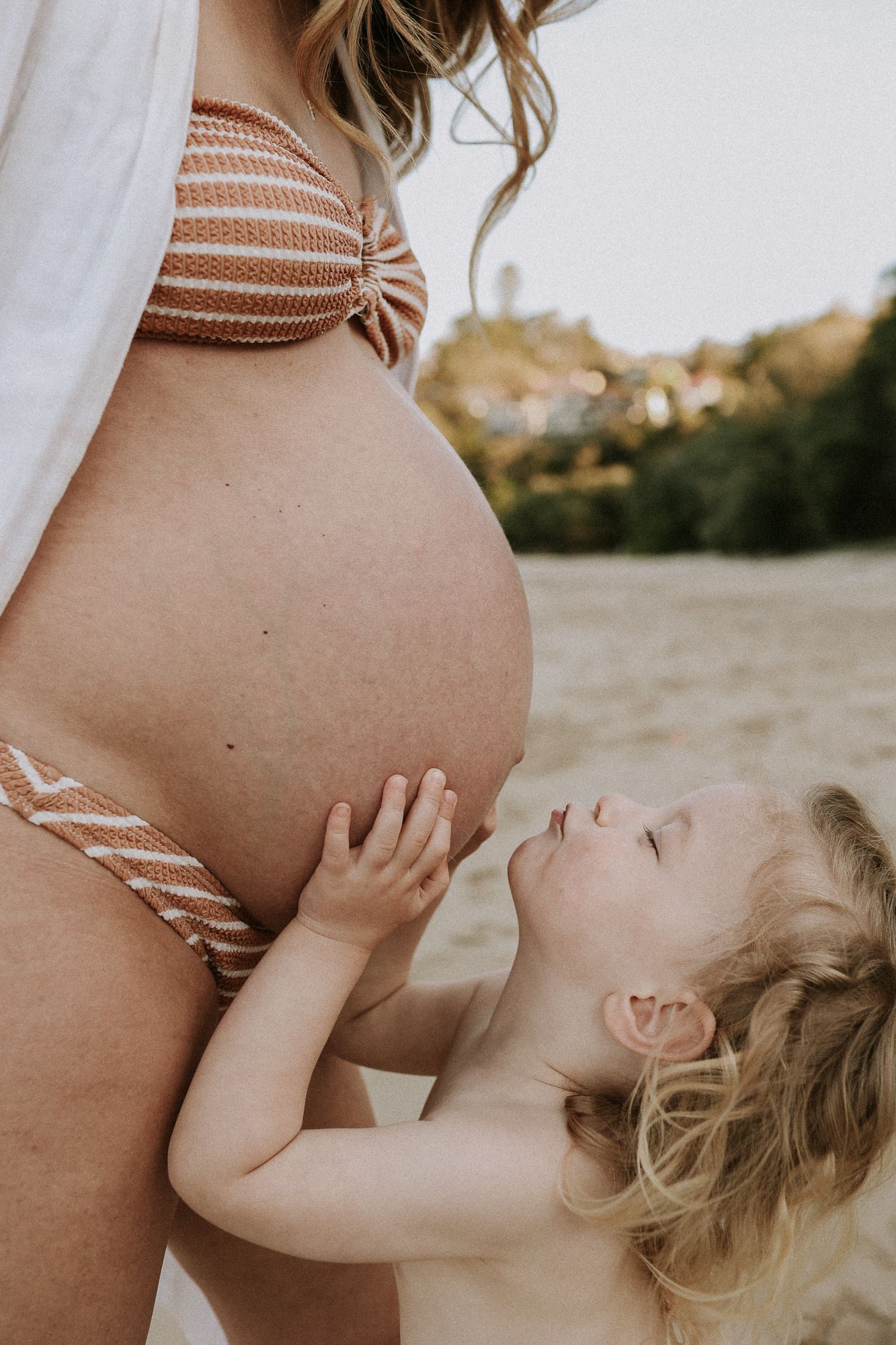A child and a mother at a beach with a maternity photographer