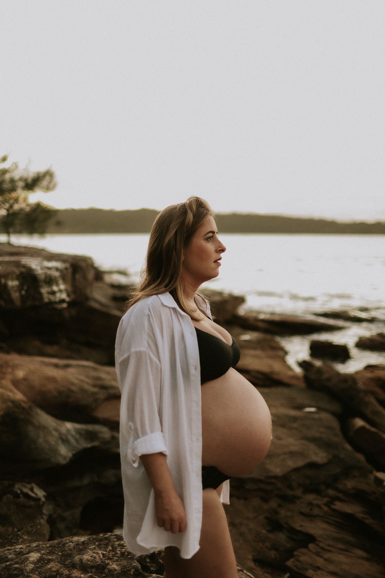 An expecting mother on Sydney’s Northern Beaches, walking barefoot along the shoreline, the ocean breeze gently lifting her dress.