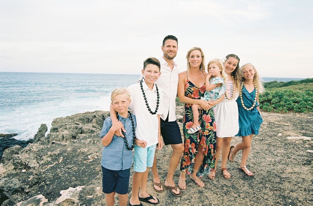 Family group photo on rocky coastal overlook with ocean in background.