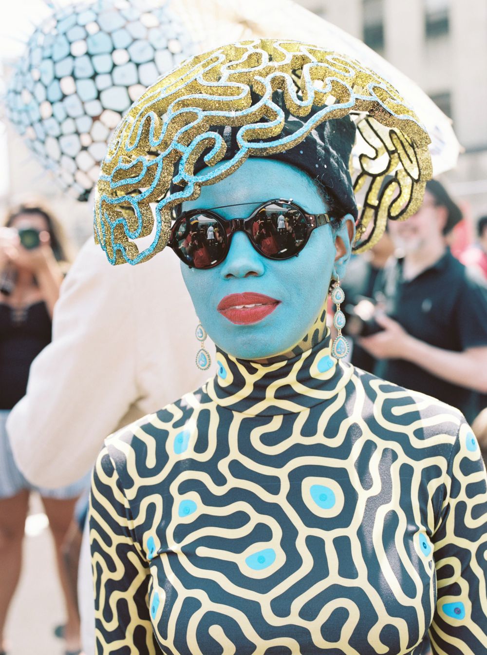 Performance art costume in blue and gold with elaborate geometric patterns and headdress.
