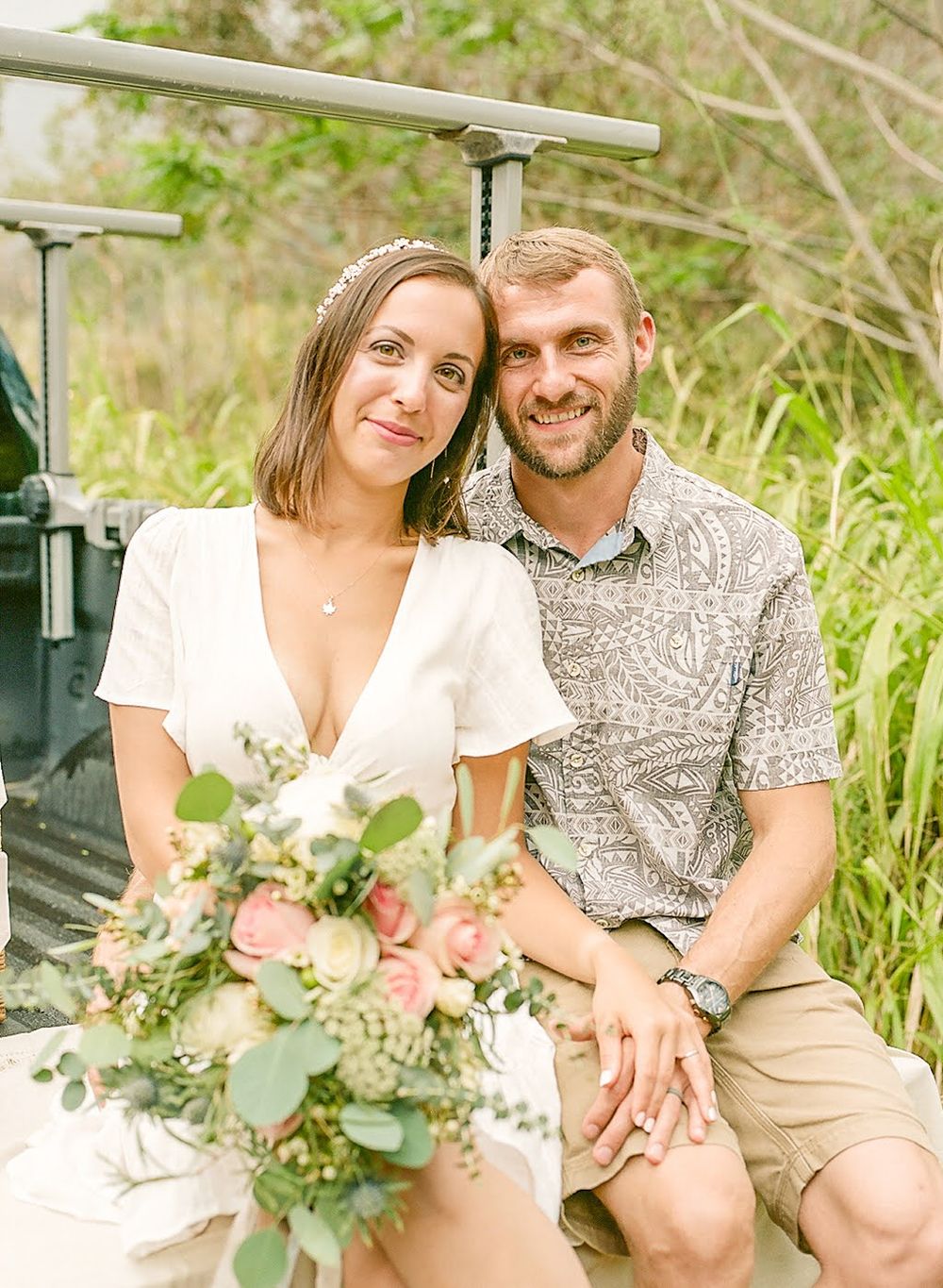 A couple poses together on a truck tailgate surrounded by tall grass.