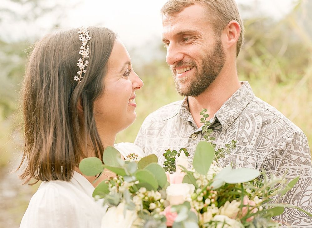 A romantic outdoor portrait of a couple with wedding flowers and natural scenery.