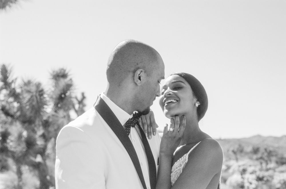 Black and white photo of newlyweds sharing a joyful laugh during their wedding photoshoot.