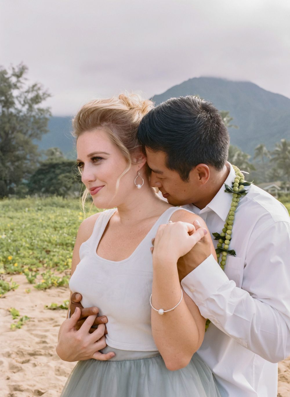 Romantic couple shares intimate moment during wedding photoshoot in mountain landscape.