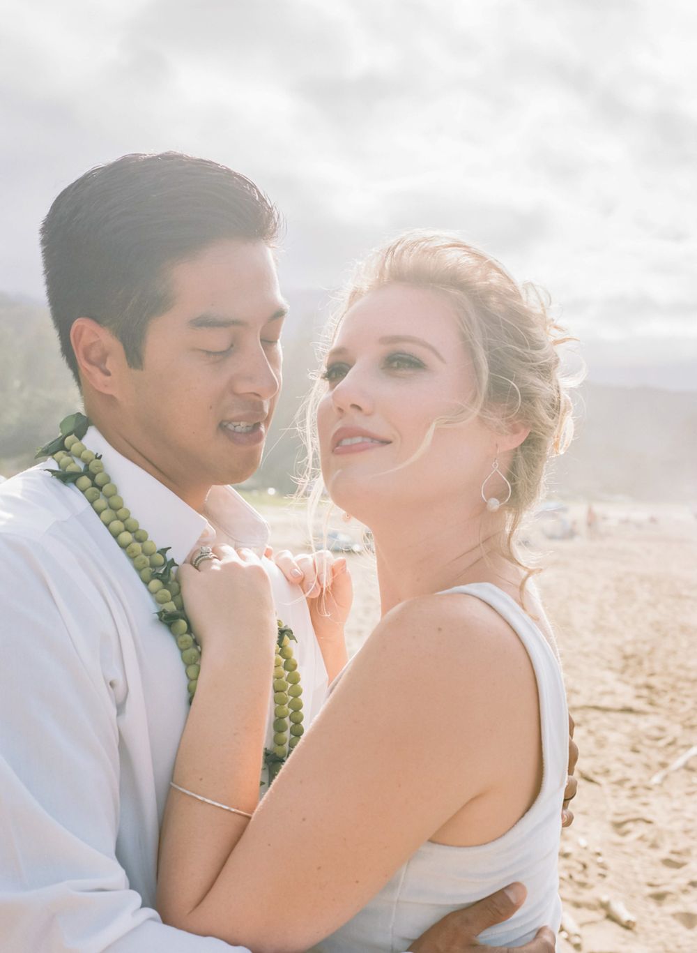 Joyful couple shares intimate moment during beach wedding photo session in Hawaii.