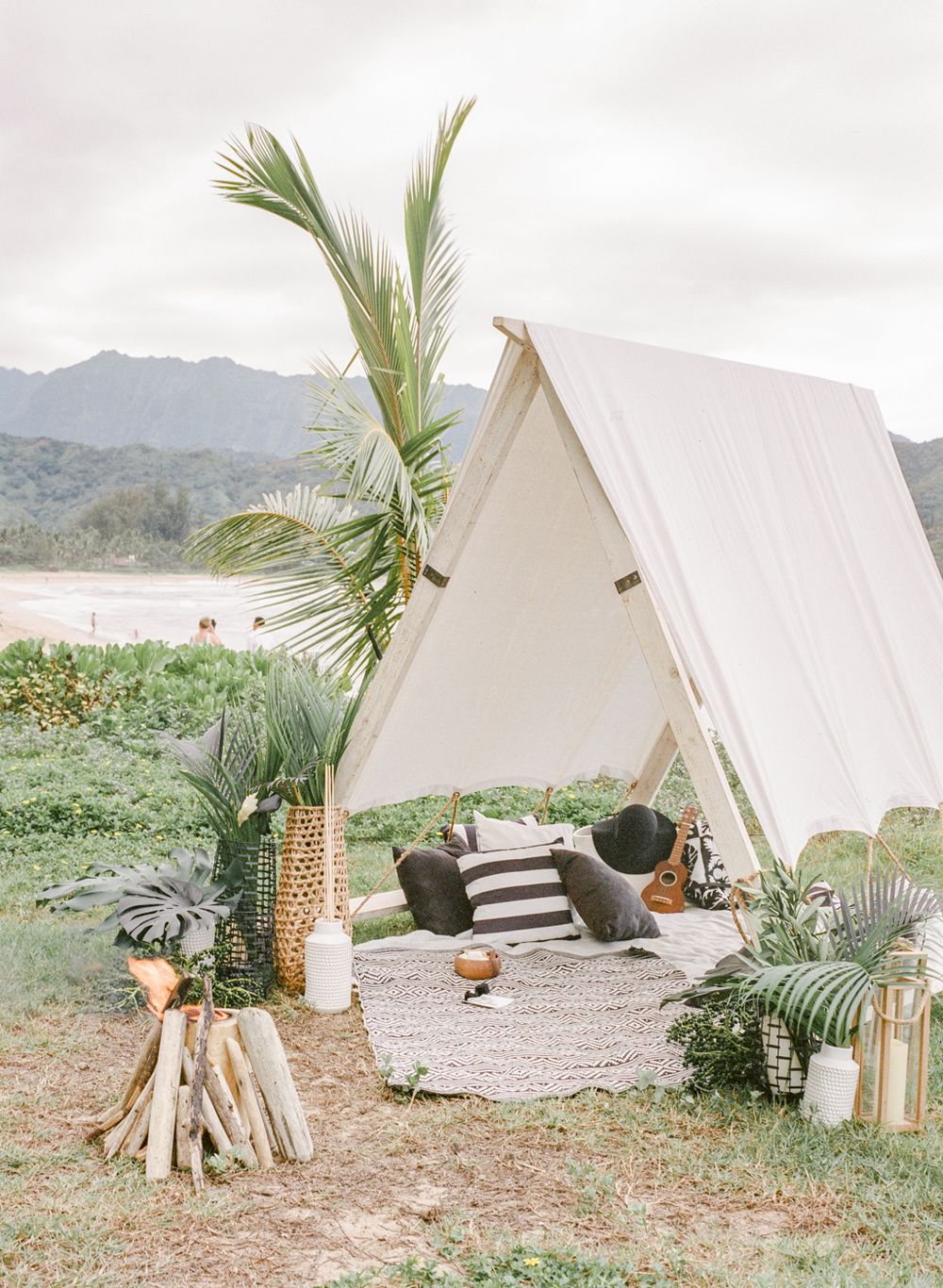 White A-frame tent decorated with tropical palms and beach decor for Hawaii wedding.