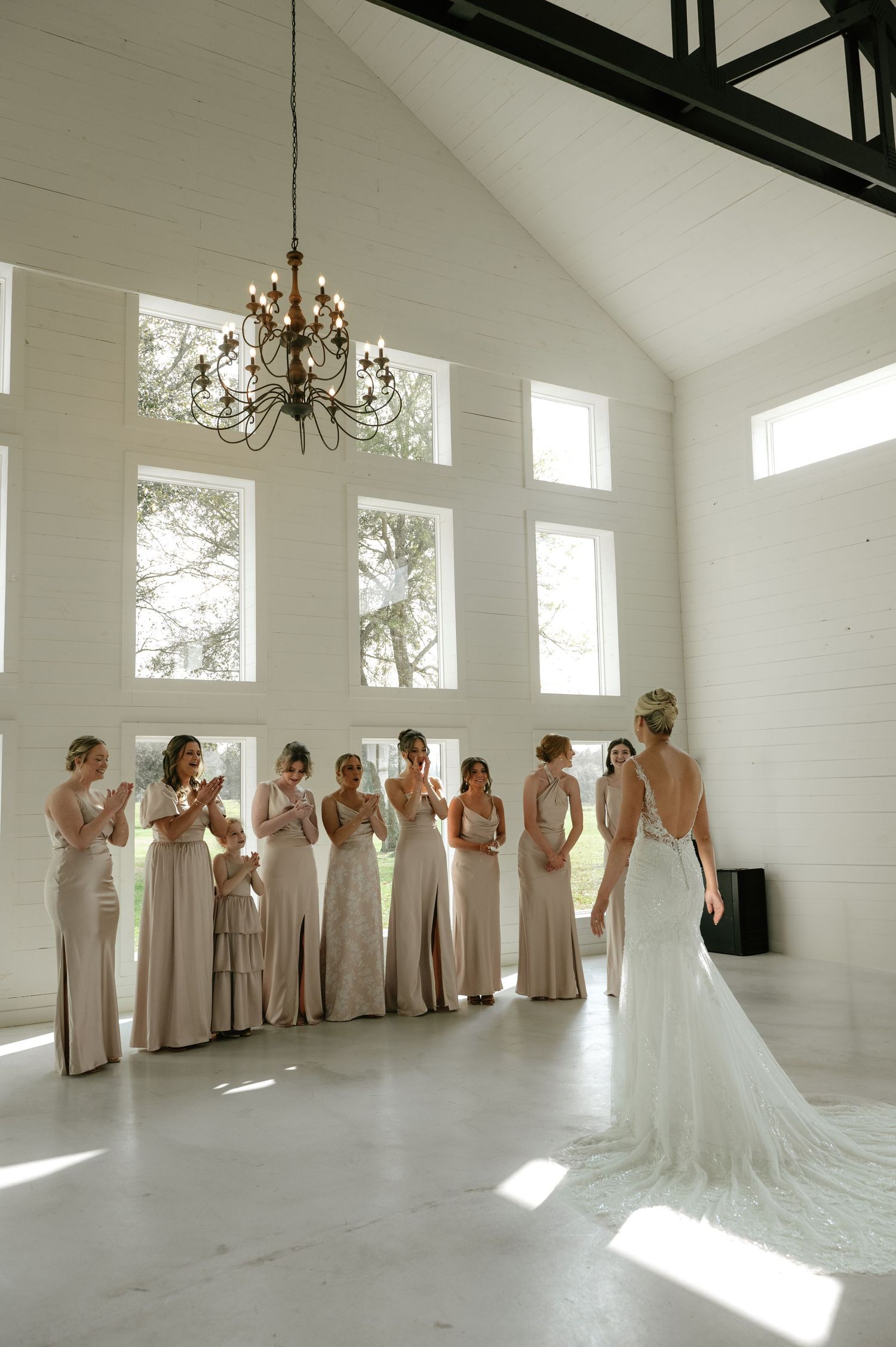 Elegant white wedding venue with draped fabric ceiling, chandelier and arched windows creating romantic atmosphere.