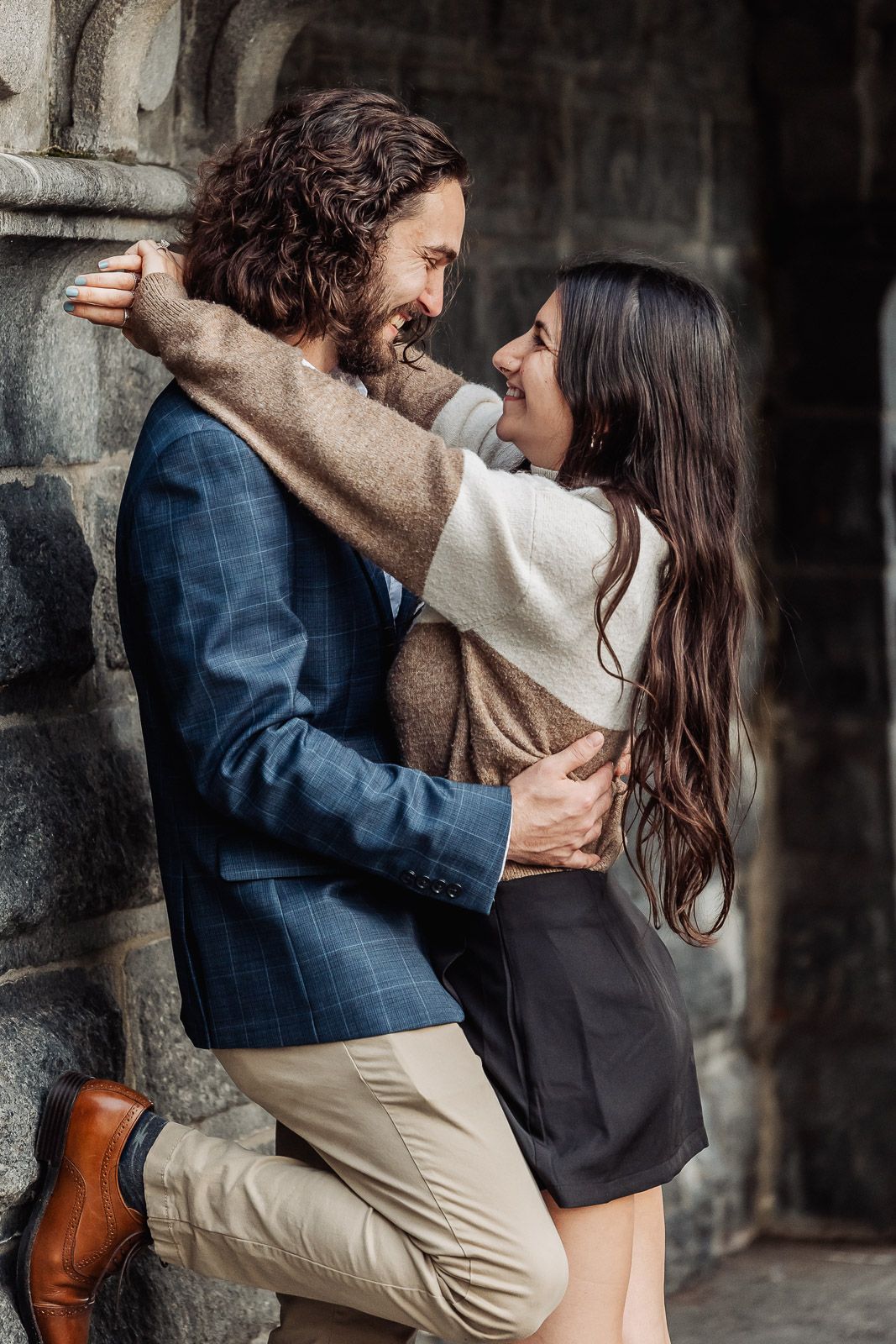 A romantic embrace against a stone archway with elegant formal attire.