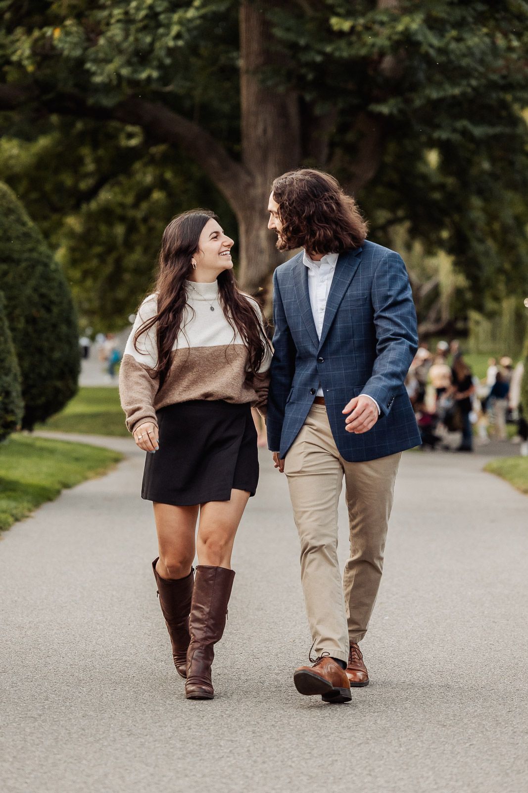 A couple walking together on a park path wearing coordinated autumn outfits.