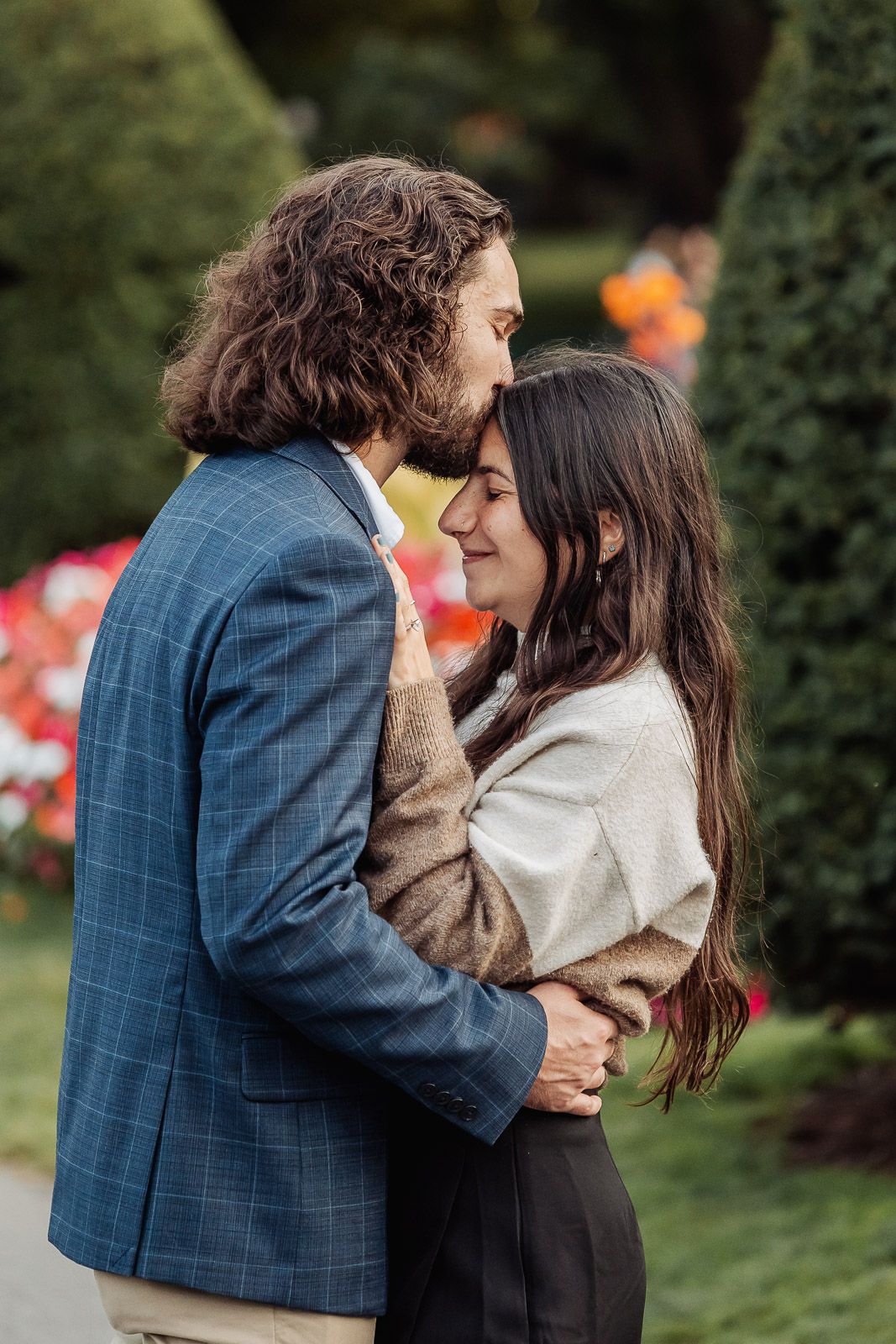 A tender moment shared between a couple in a garden with blooming flowers.