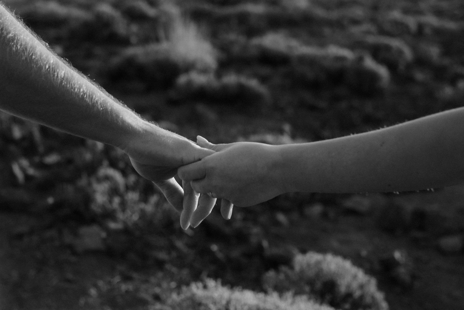 A black and white close-up of two hands touching in an intimate moment. Tenerife Wedding Photographer at Teide.
