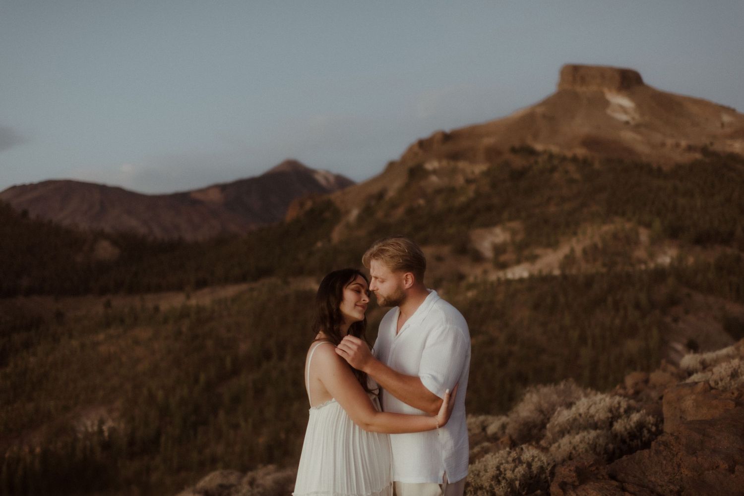 Couple shares intimate moment on mountainside during sunset photography session. Tenerife Wedding Photographer at Teide.