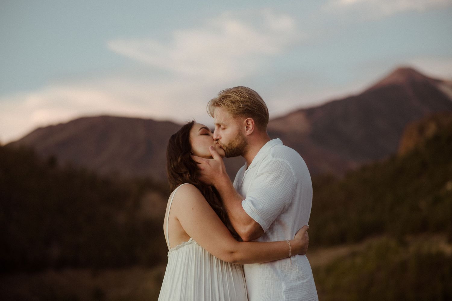 A warm sunset engagement photo with mountains and soft clouds in the background. Tenerife Wedding Photographer at Teide.