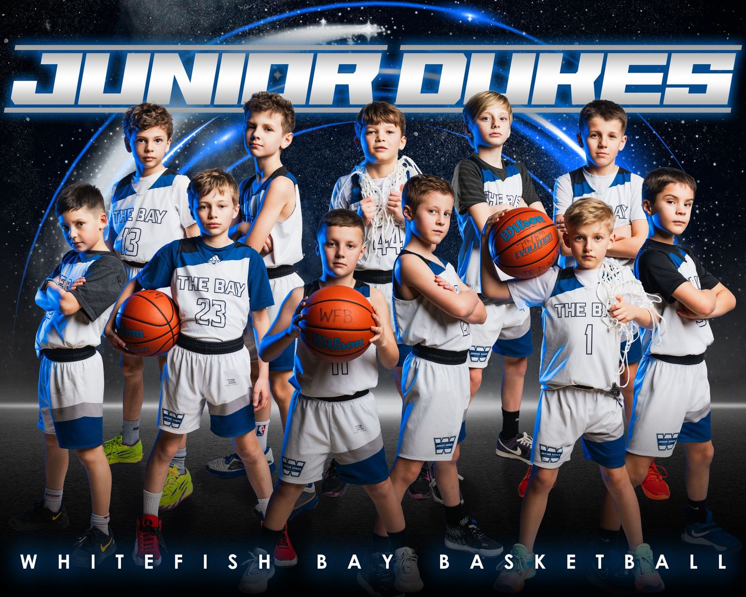 Youth basketball team poses for team photo in blue and white uniforms with basketballs against dark background.